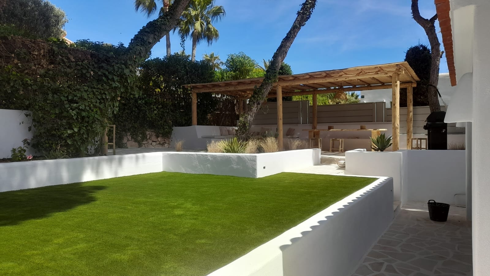 Modern white walled garden with artificial grass and pergola