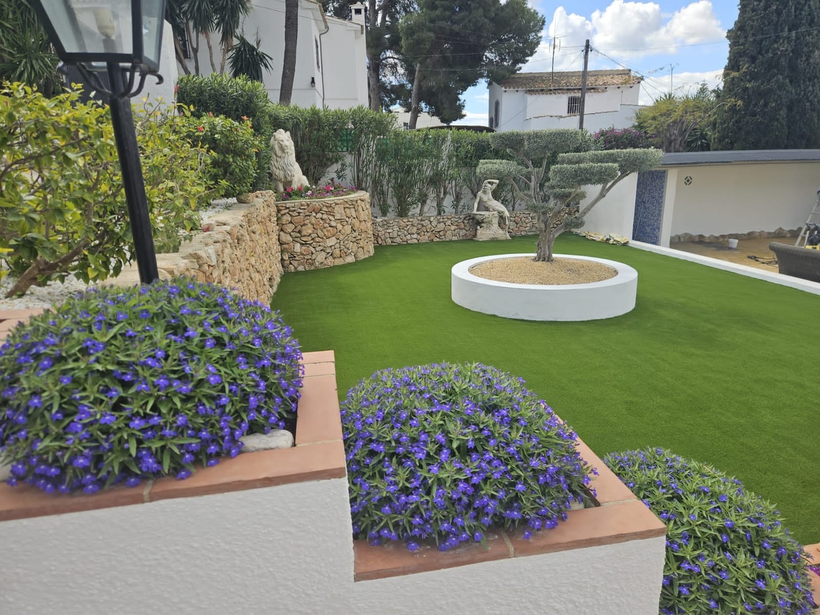 Mediterranean garden with purple flowers, stone wall and olive tree Costa Blanca